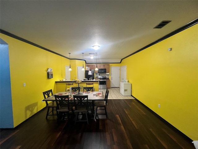 dining area featuring wood-type flooring and crown molding