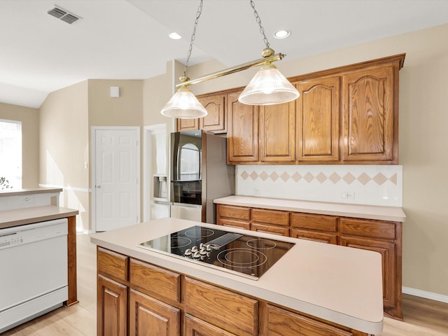 kitchen featuring decorative backsplash, black electric stovetop, white dishwasher, pendant lighting, and stainless steel refrigerator