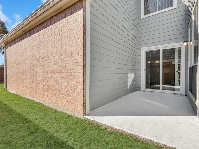 view of side of property featuring a lawn and a patio