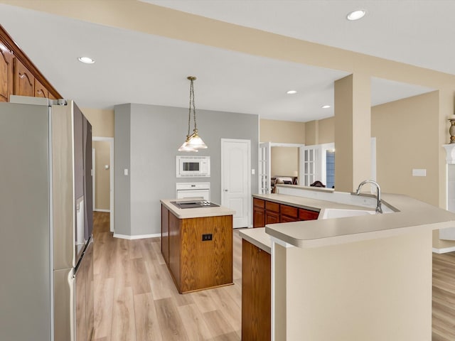 kitchen with stainless steel refrigerator, a center island, kitchen peninsula, decorative light fixtures, and white microwave