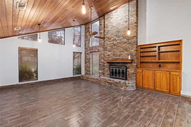 unfurnished living room with ceiling fan, wooden ceiling, a fireplace, and a high ceiling