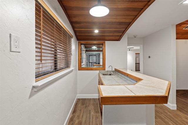 kitchen with kitchen peninsula, tile countertops, sink, and wooden ceiling