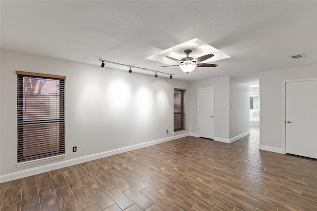 spare room with a textured ceiling, track lighting, and ceiling fan