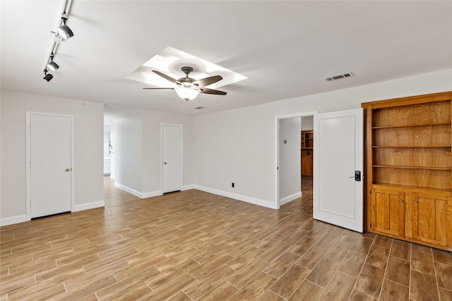 spare room featuring ceiling fan, rail lighting, and a textured ceiling