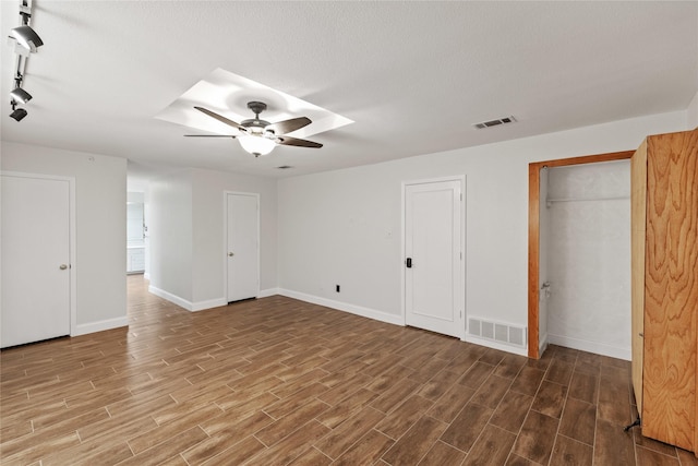 unfurnished bedroom with ceiling fan, track lighting, and two closets