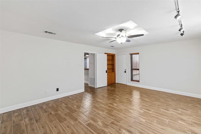 unfurnished room with a skylight, ceiling fan, and track lighting