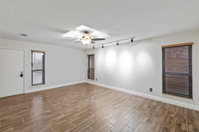 empty room with ceiling fan, a textured ceiling, and track lighting