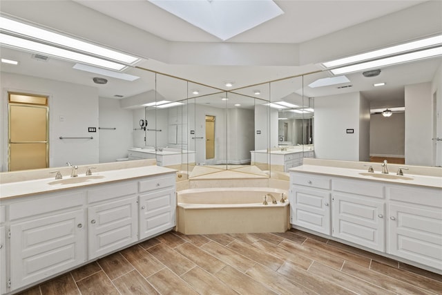 bathroom featuring a skylight, a bathtub, and vanity