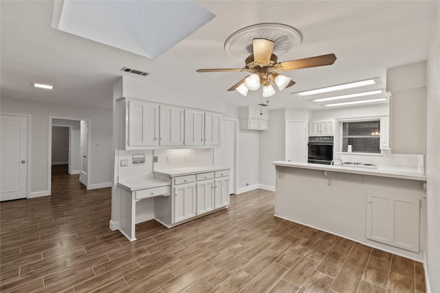 kitchen featuring a kitchen breakfast bar, kitchen peninsula, ceiling fan, and white cabinets