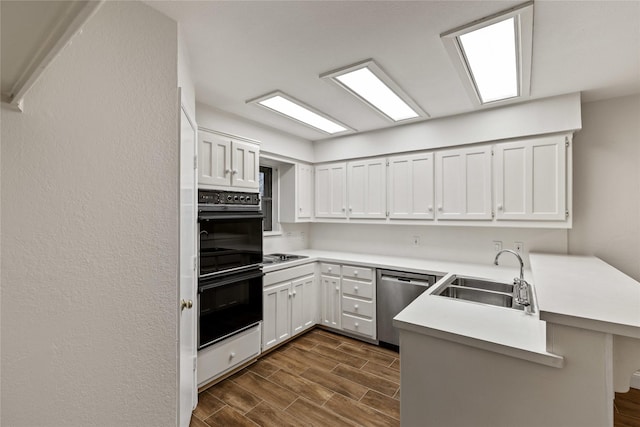 kitchen with white cabinets, kitchen peninsula, sink, and black double oven