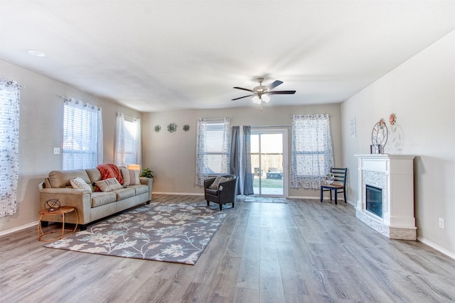 living room featuring light hardwood / wood-style floors, a tile fireplace, and ceiling fan