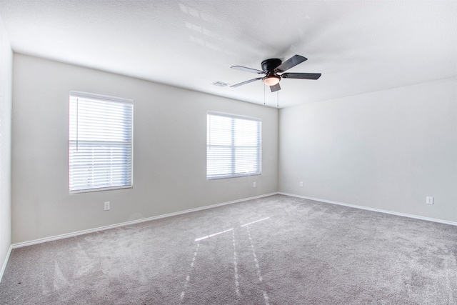 carpeted empty room featuring a wealth of natural light and ceiling fan