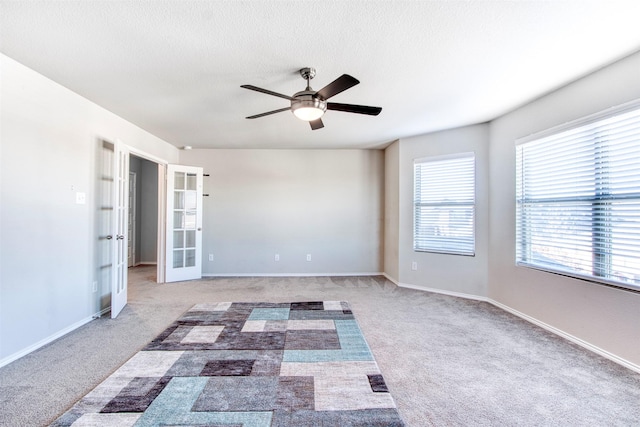 spare room with carpet, ceiling fan, and french doors