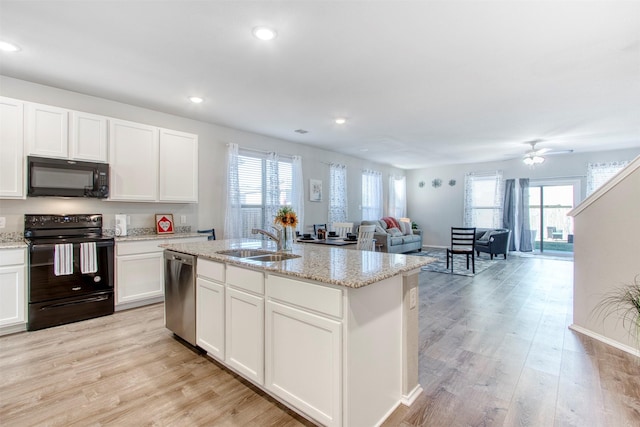 kitchen featuring a kitchen island with sink, black appliances, white cabinets, sink, and light wood-type flooring