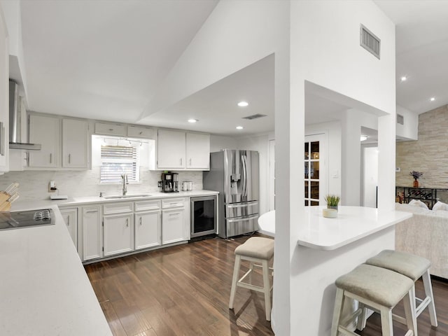 kitchen with a kitchen breakfast bar, beverage cooler, sink, white cabinetry, and stainless steel fridge with ice dispenser