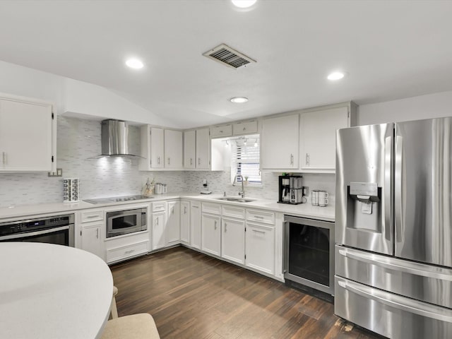 kitchen featuring white cabinetry, wine cooler, sink, appliances with stainless steel finishes, and wall chimney exhaust hood