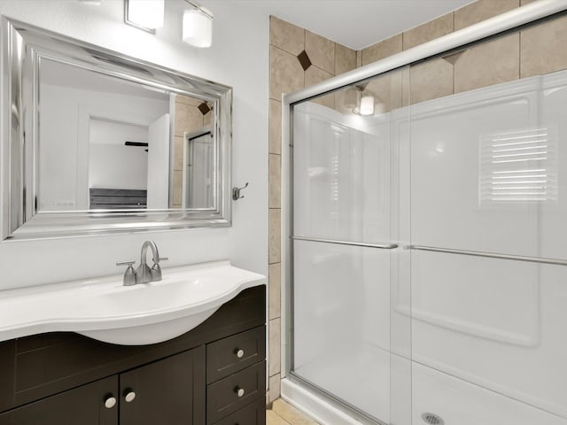 bathroom featuring a shower with shower door and vanity