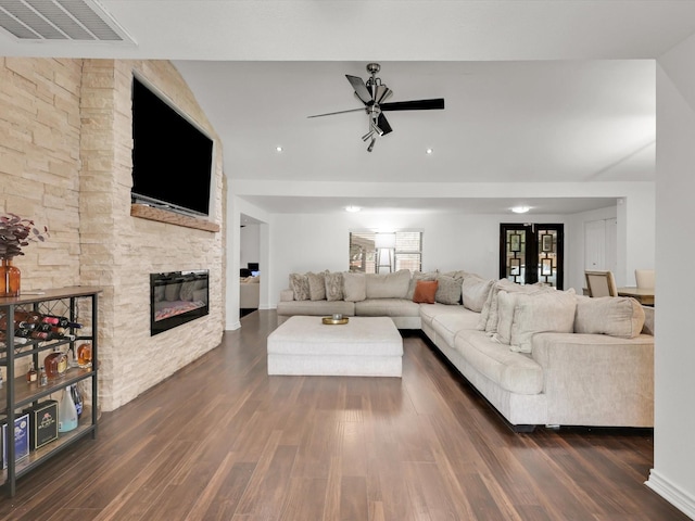 living room with ceiling fan, dark wood-type flooring, french doors, and a stone fireplace