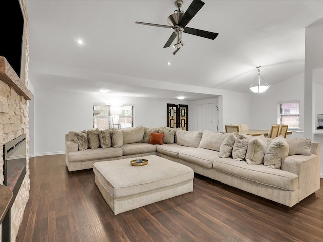 living room with ceiling fan, vaulted ceiling, dark wood-type flooring, and a fireplace