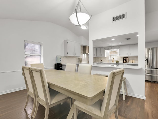 dining space with dark hardwood / wood-style flooring and vaulted ceiling