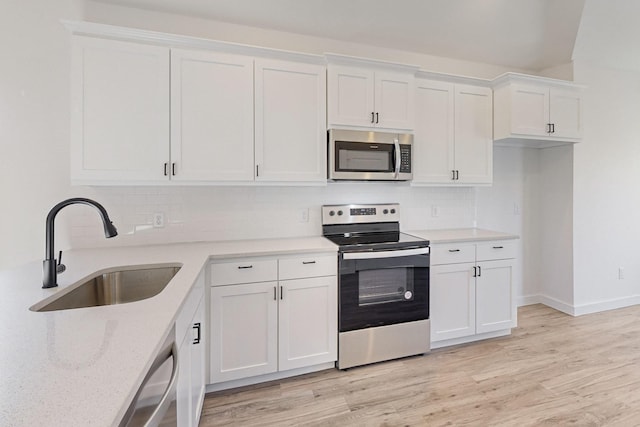 kitchen featuring stainless steel appliances, white cabinetry, light hardwood / wood-style floors, and sink