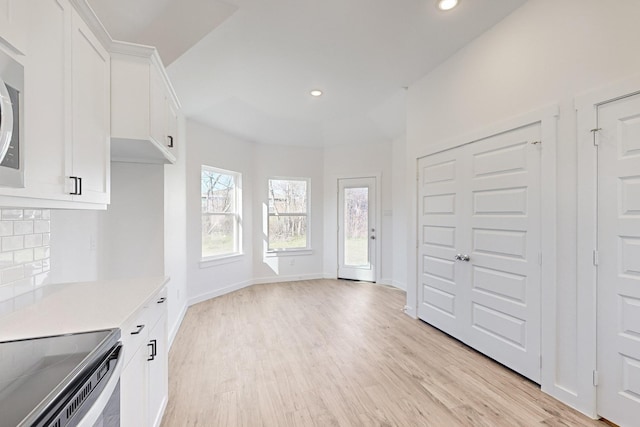 interior space featuring white cabinets, light hardwood / wood-style floors, and range