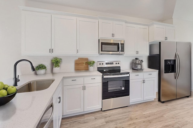 kitchen with sink, stainless steel appliances, backsplash, white cabinets, and light wood-type flooring