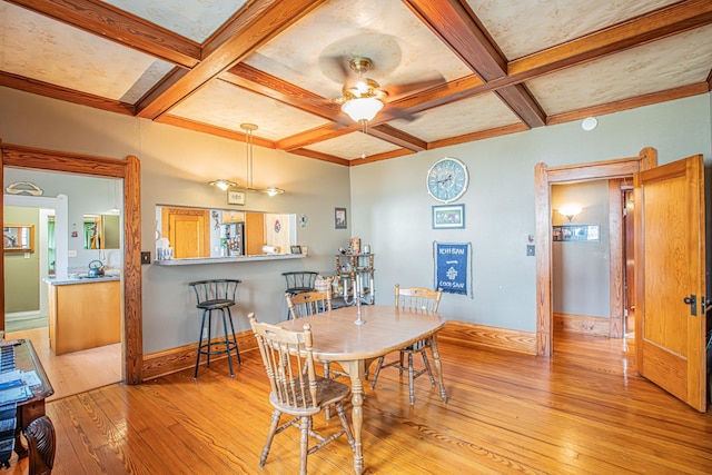 dining room with coffered ceiling, beam ceiling, light hardwood / wood-style flooring, and ceiling fan