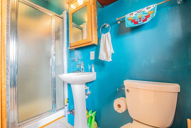 bathroom featuring a shower with door and toilet