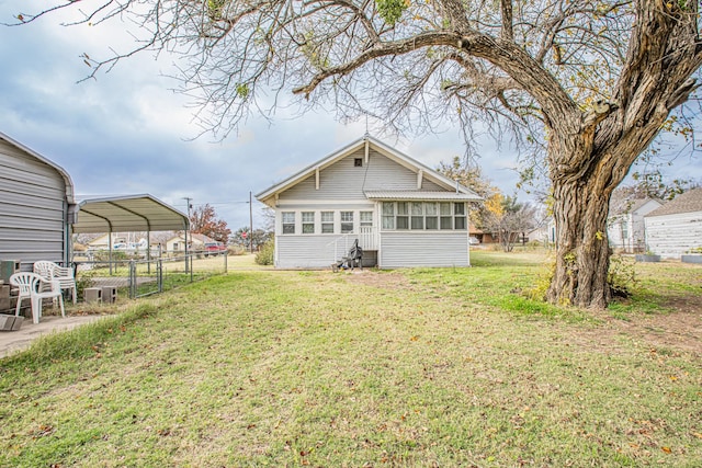 rear view of property with a carport, a sunroom, and a lawn