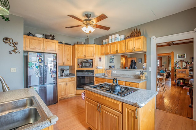 kitchen with light hardwood / wood-style floors, a center island, sink, and black appliances