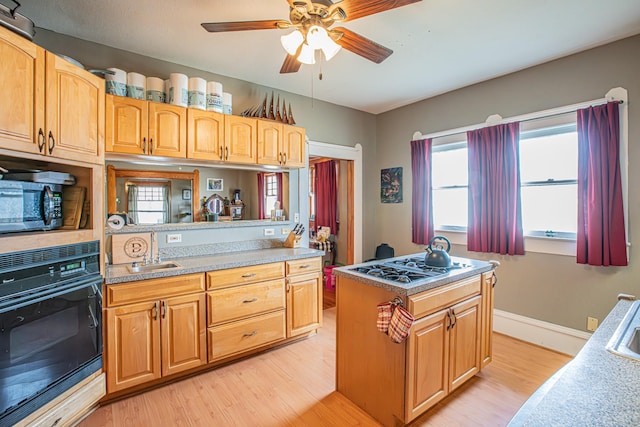 kitchen featuring a center island, sink, black oven, and light hardwood / wood-style flooring