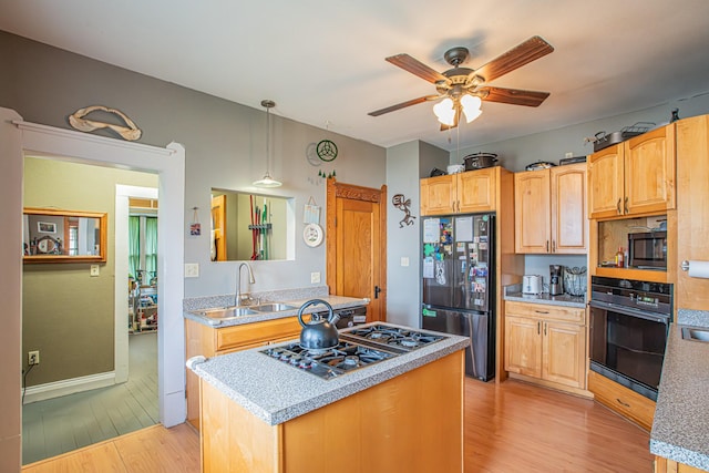 kitchen with black appliances, sink, hanging light fixtures, ceiling fan, and light hardwood / wood-style floors