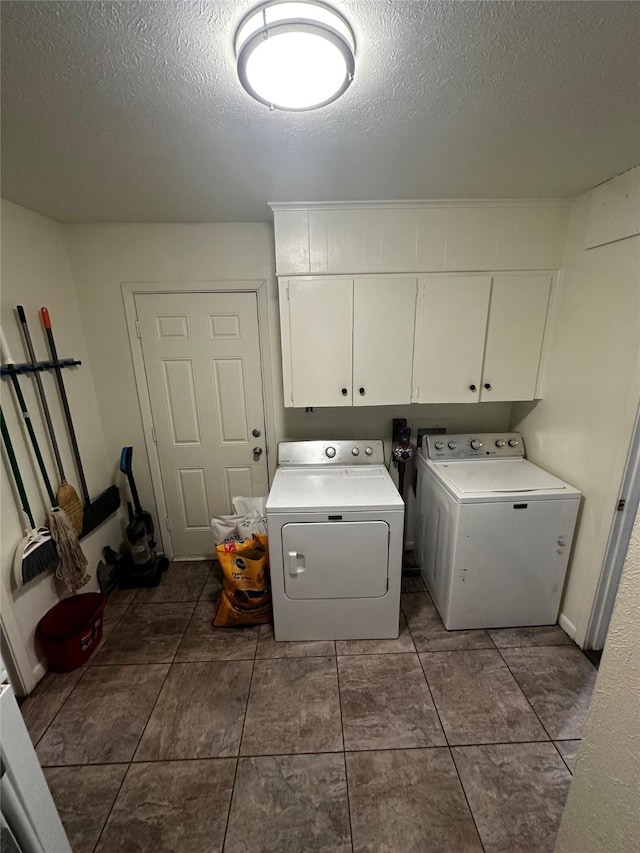 washroom featuring a textured ceiling, cabinets, and washing machine and clothes dryer