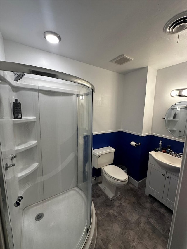 bathroom with vanity, toilet, and a shower with door