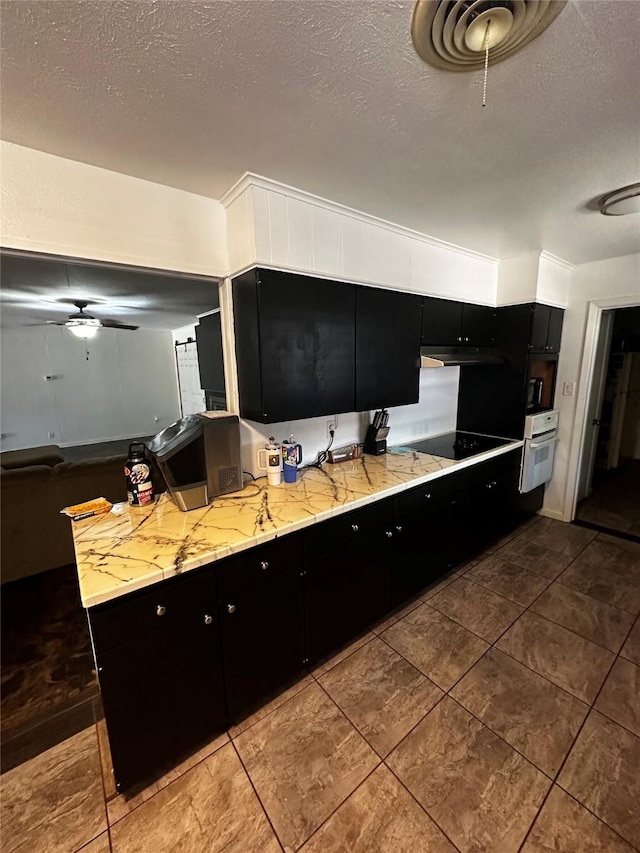 kitchen featuring black electric stovetop, ceiling fan, kitchen peninsula, white oven, and a textured ceiling