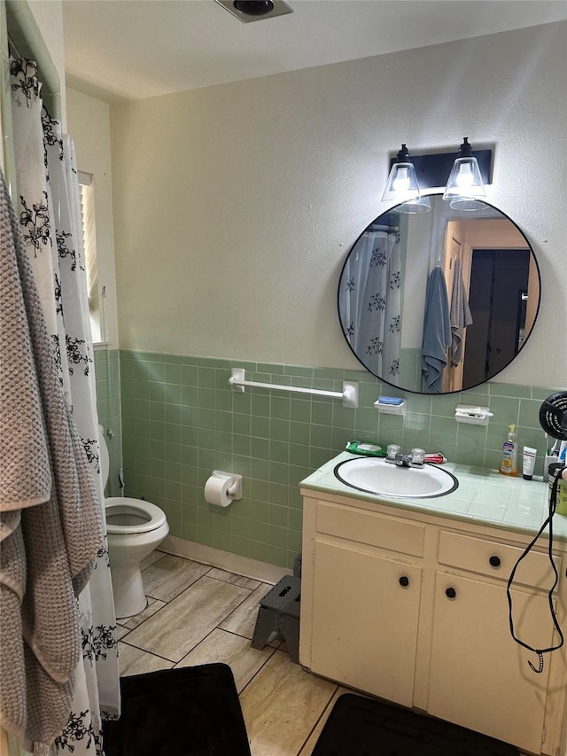 bathroom featuring vanity, tile walls, and toilet