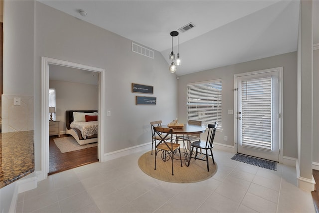 dining area featuring light tile patterned floors, a healthy amount of sunlight, and vaulted ceiling