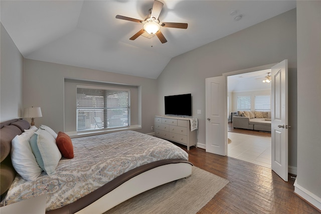 bedroom with multiple windows, ceiling fan, dark wood-type flooring, and lofted ceiling