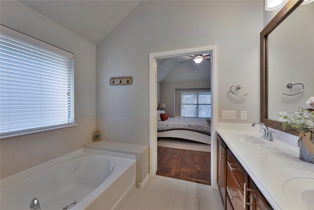 bathroom featuring a tub to relax in, tile patterned floors, vanity, vaulted ceiling, and ceiling fan