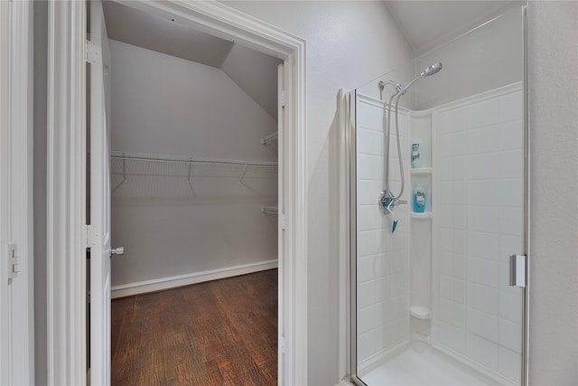 bathroom featuring hardwood / wood-style flooring, walk in shower, and vaulted ceiling