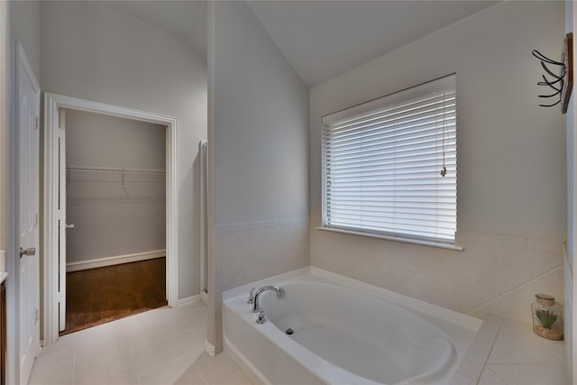 bathroom with tile patterned floors, a tub to relax in, and lofted ceiling