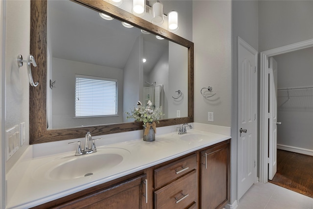 bathroom featuring tile patterned flooring, vanity, vaulted ceiling, and walk in shower