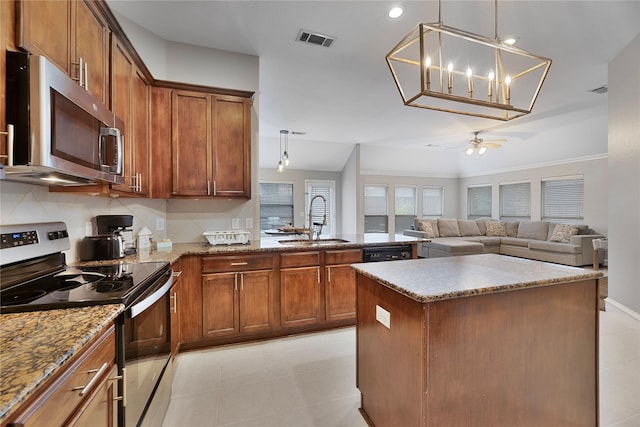 kitchen featuring sink, a center island, stainless steel appliances, pendant lighting, and ceiling fan with notable chandelier