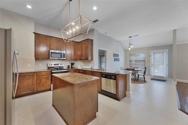 kitchen featuring kitchen peninsula, appliances with stainless steel finishes, light stone counters, pendant lighting, and a kitchen island