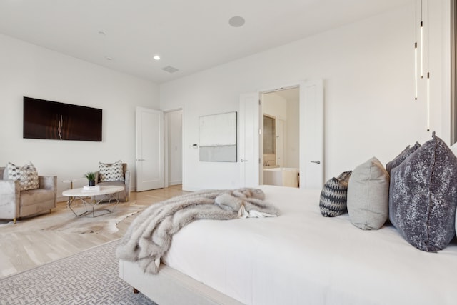 bedroom featuring ensuite bath and light wood-type flooring