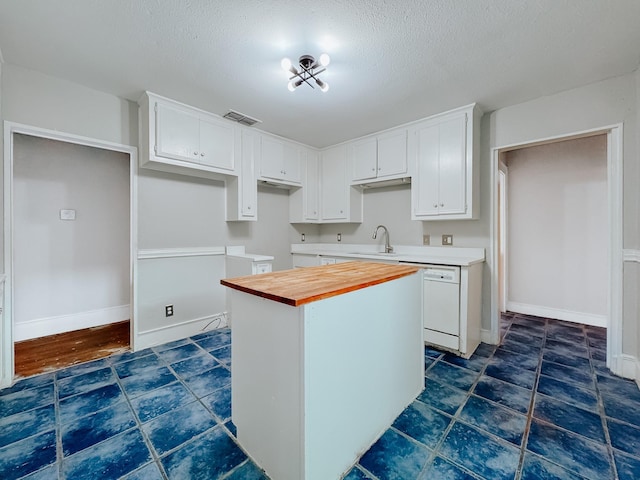 kitchen with wood counters, a textured ceiling, white dishwasher, a kitchen island, and white cabinetry