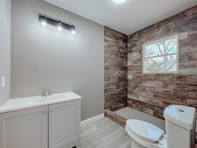 bathroom featuring hardwood / wood-style floors, vanity, toilet, and tiled shower