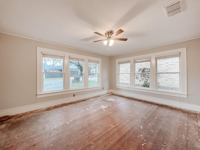 unfurnished room featuring hardwood / wood-style floors, ceiling fan, a healthy amount of sunlight, and ornamental molding