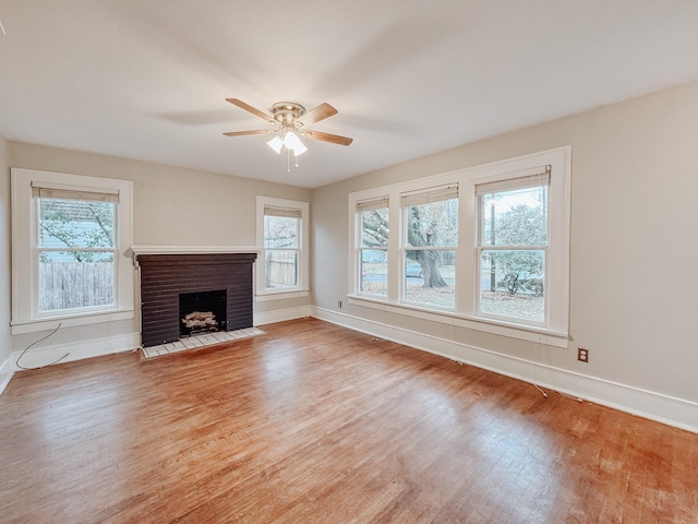 unfurnished living room with light hardwood / wood-style flooring, a brick fireplace, and ceiling fan